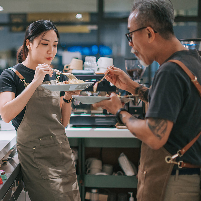 2 restaurant employees enjoying a meal together in the kitchen