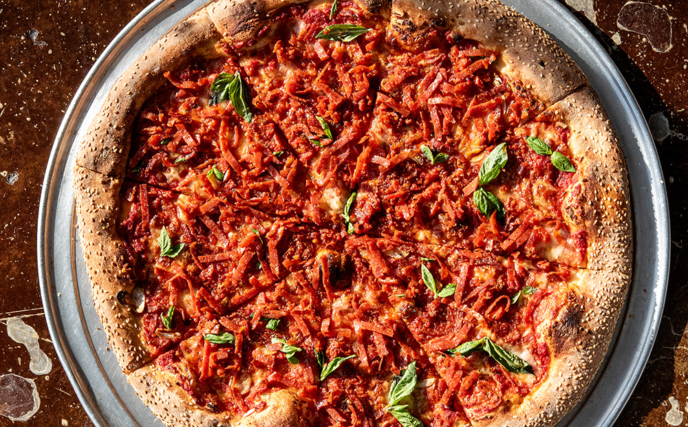 Overhead shot of pizza with ribbon pepperoni and basil