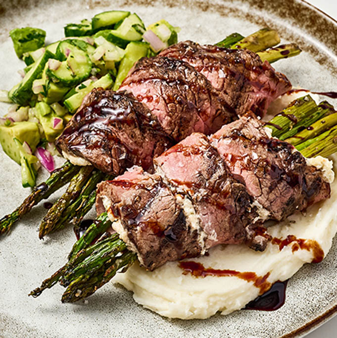 Asparagus and Herbed Cheese Stuffed Flank Steak Rolls on Creamy Mashed Potatoes